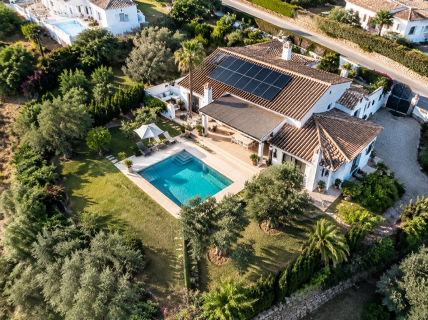 Vista aérea de una villa con piscina y paneles solares en el tejado